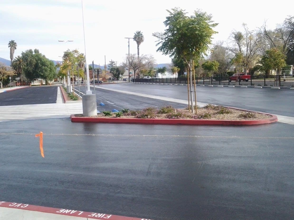 Fresh asphalt around a landscaped median island edged with a red fire-lane curb