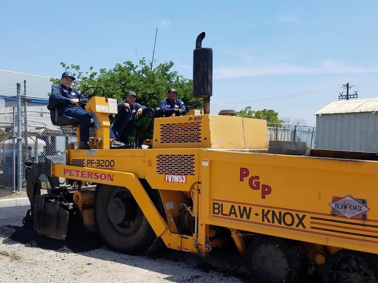 Three crew members aboard a Peterson Blaw-Knox PF-3200 asphalt paver