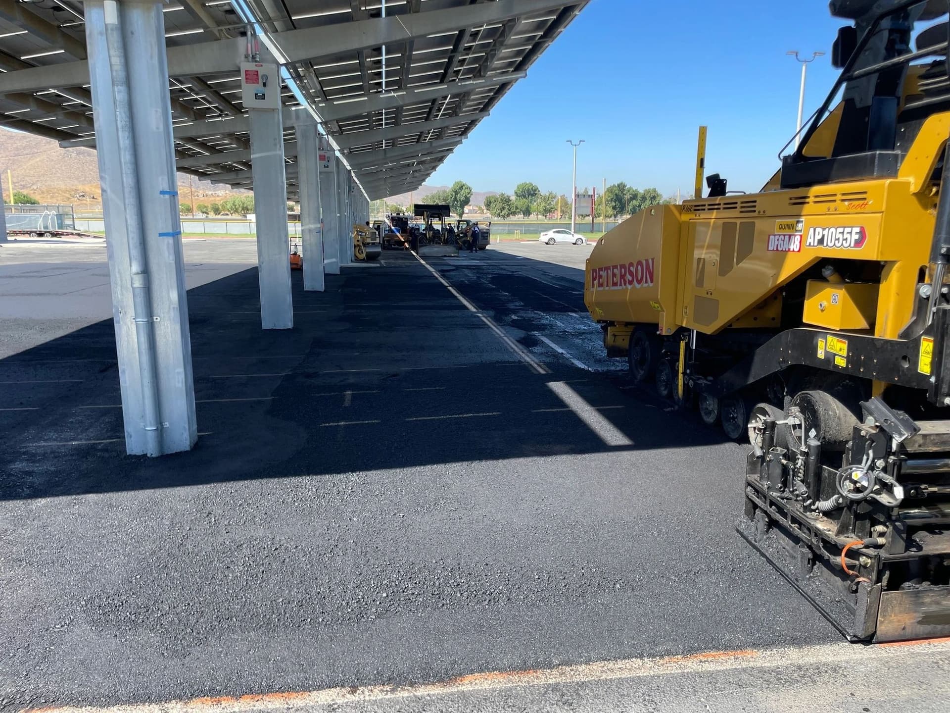 Peterson asphalt paver laying new asphalt along a row of solar carports