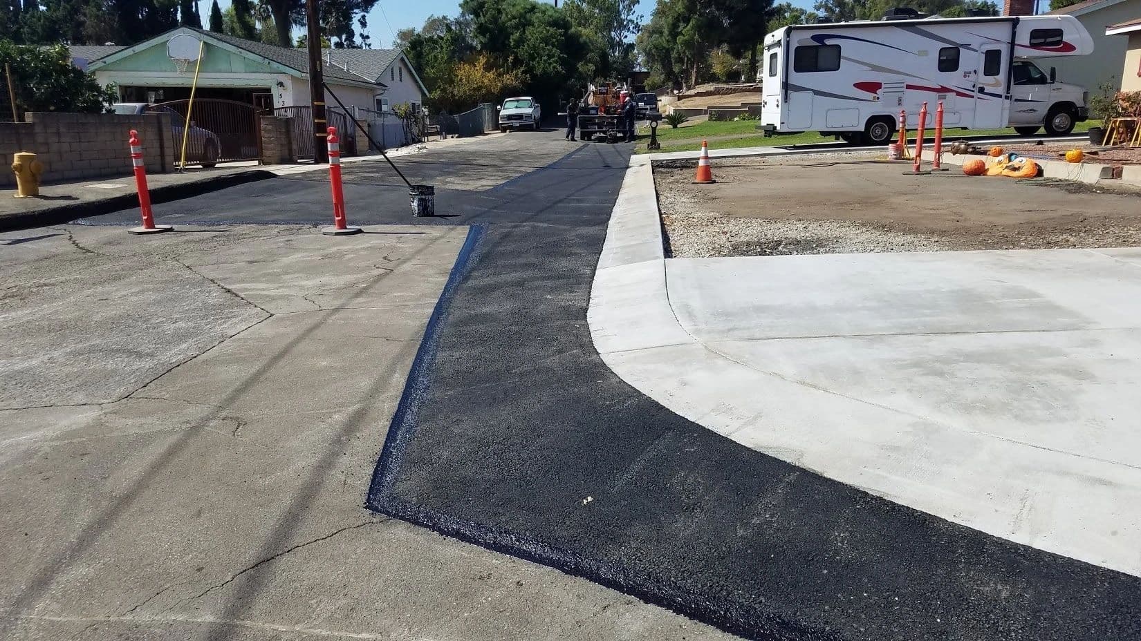 New asphalt strip placed between existing pavement and a newly poured concrete apron