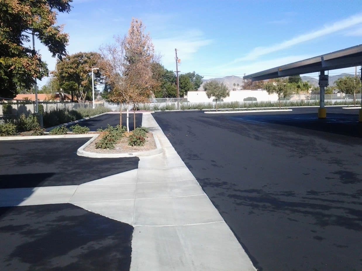 Freshly paved parking lot beside a new concrete walkway and landscaped planter